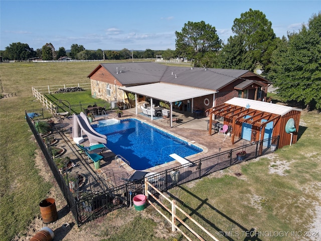 view of swimming pool featuring a water slide, a patio area, a rural view, a diving board, and a lawn