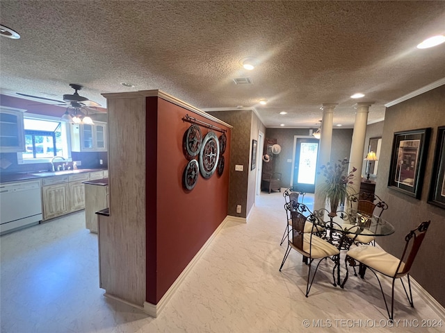 interior space with decorative columns, sink, crown molding, and a textured ceiling