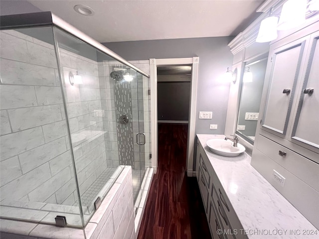 bathroom with a shower with shower door, hardwood / wood-style floors, and vanity