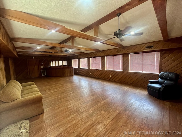 living room with hardwood / wood-style floors, ceiling fan, wooden walls, and a textured ceiling