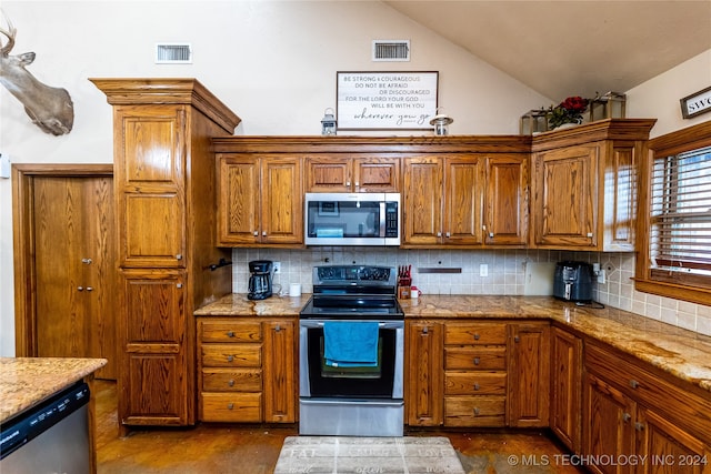 kitchen with light stone counters, appliances with stainless steel finishes, tasteful backsplash, and lofted ceiling