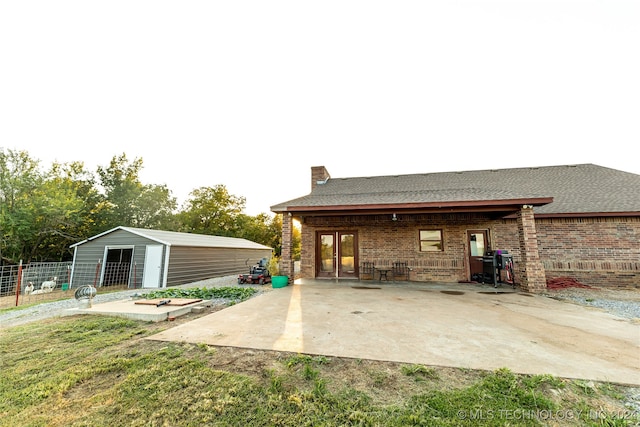 back of property with a patio, a yard, and an outbuilding