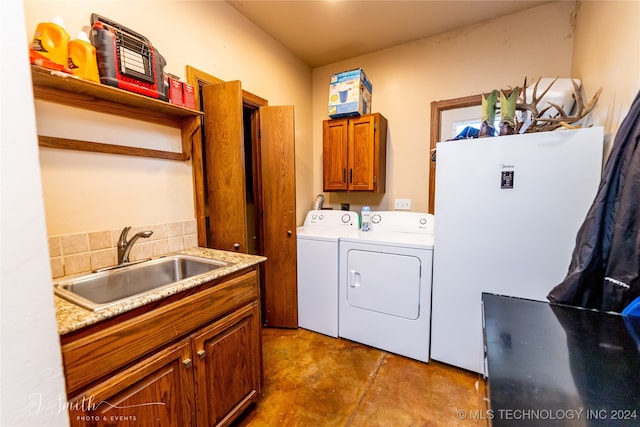 clothes washing area with cabinets, sink, and washer and dryer