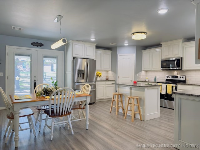 kitchen with light hardwood / wood-style floors, tasteful backsplash, appliances with stainless steel finishes, and white cabinets