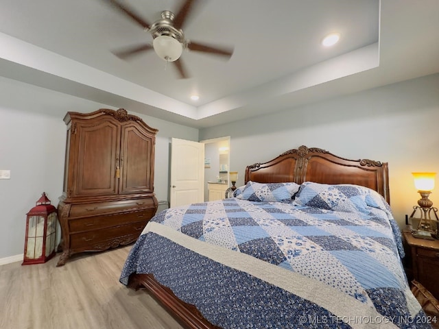 bedroom featuring a tray ceiling, light wood-type flooring, and ceiling fan