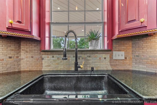 kitchen with dark stone countertops, sink, and decorative backsplash