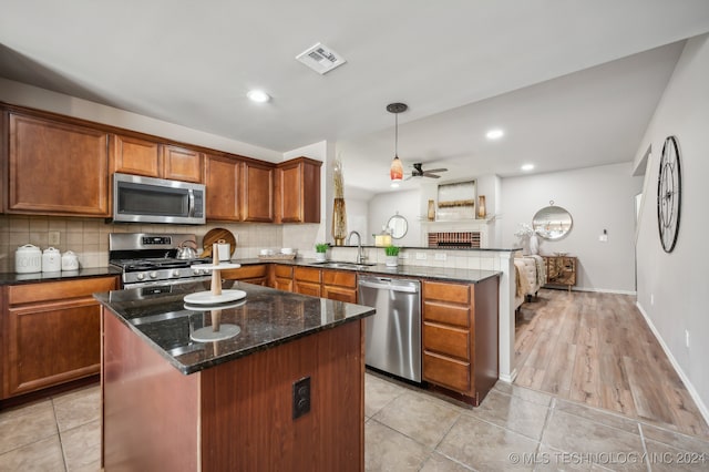 kitchen with kitchen peninsula, stainless steel appliances, ceiling fan, decorative light fixtures, and light hardwood / wood-style floors