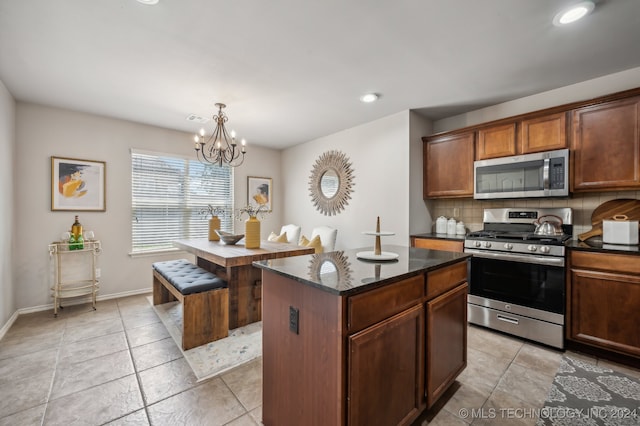 kitchen featuring decorative backsplash, appliances with stainless steel finishes, decorative light fixtures, a notable chandelier, and a center island