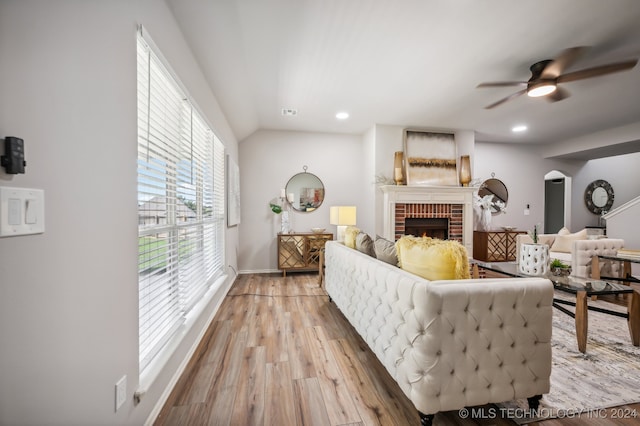 living room featuring ceiling fan, a fireplace, light hardwood / wood-style floors, and lofted ceiling