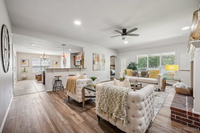 living room featuring plenty of natural light, ceiling fan with notable chandelier, and light hardwood / wood-style flooring