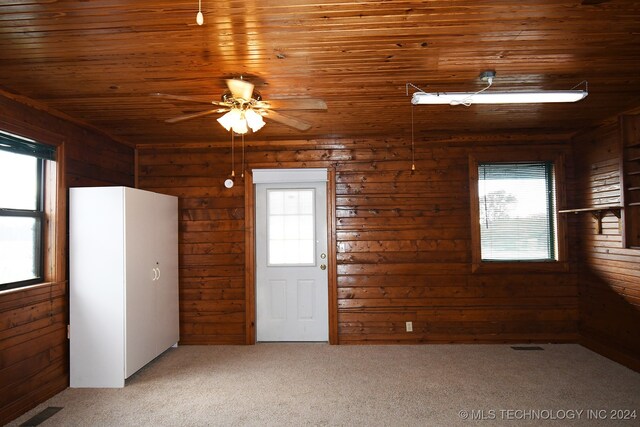 empty room featuring carpet, ceiling fan, a wealth of natural light, and wood ceiling