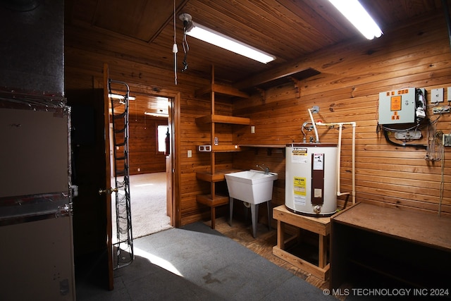 interior space with carpet flooring, wood walls, sink, and water heater