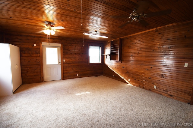 carpeted empty room with ceiling fan, wooden walls, and wood ceiling