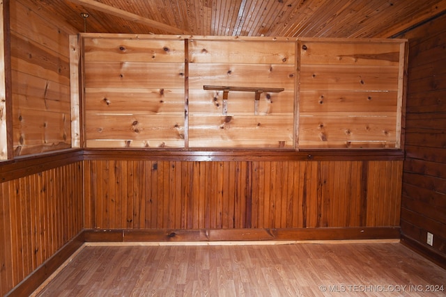 empty room featuring hardwood / wood-style floors, wooden ceiling, and wooden walls