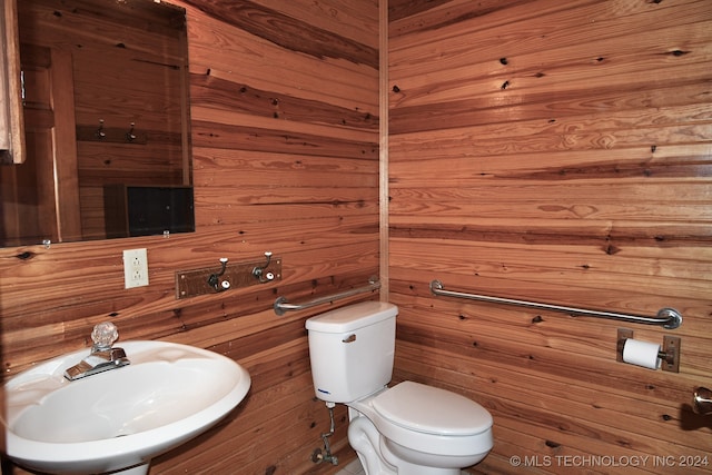 bathroom with wooden walls, sink, and toilet