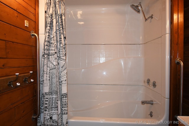 bathroom with wood walls and shower / tub combo with curtain