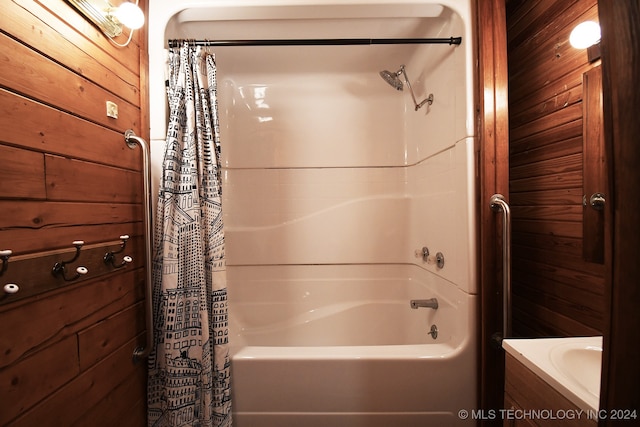 bathroom featuring shower / bath combo with shower curtain and wooden walls