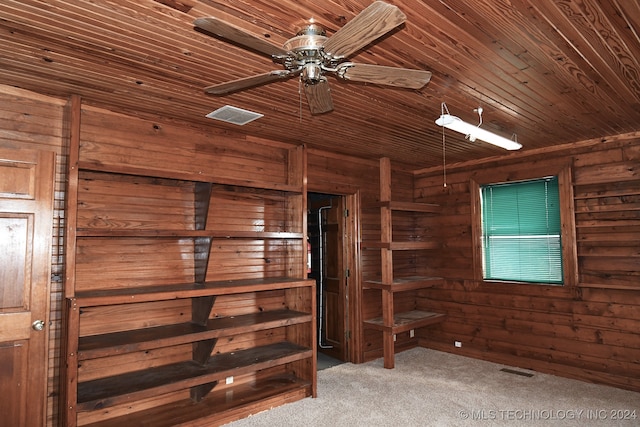 interior space featuring carpet, ceiling fan, wood ceiling, and wooden walls