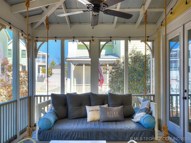 unfurnished sunroom featuring plenty of natural light, ceiling fan, and lofted ceiling with beams