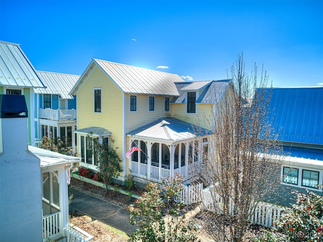 rear view of property featuring a balcony and a sunroom