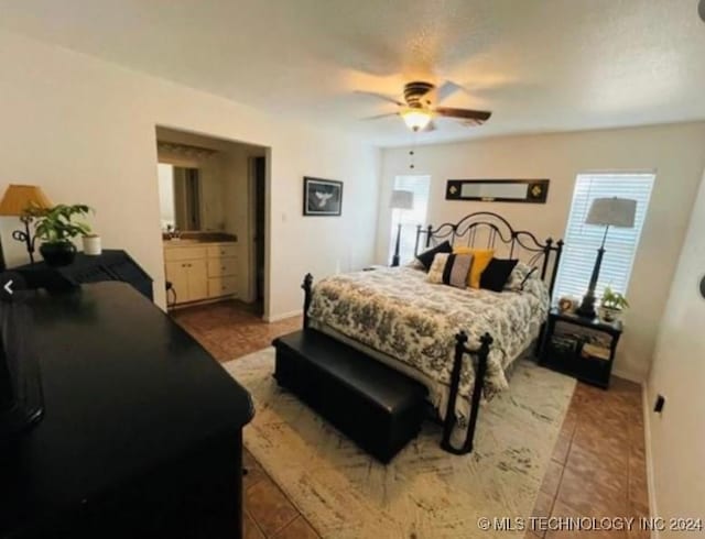 tiled bedroom featuring ensuite bath and ceiling fan