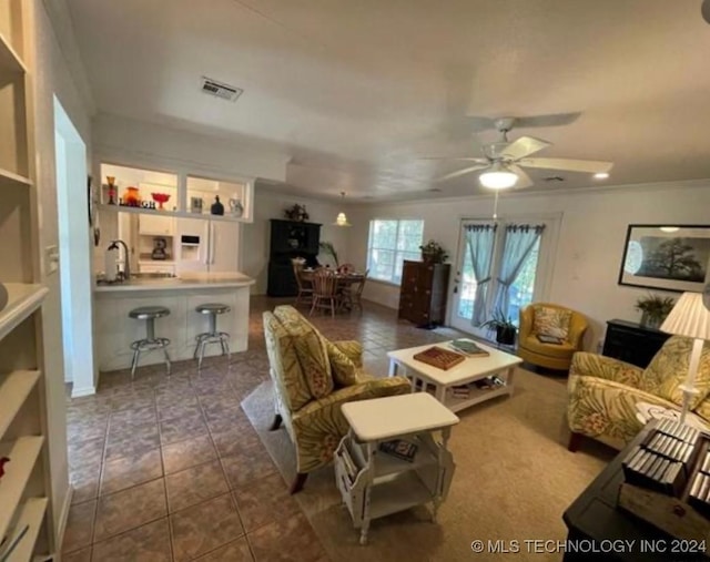 tiled living room with ceiling fan, ornamental molding, and sink