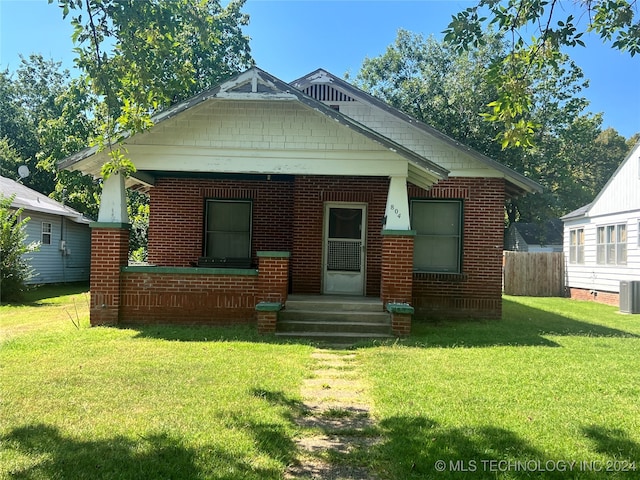 bungalow-style house featuring central AC unit and a front lawn