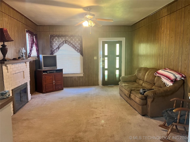 living room featuring a fireplace, wooden walls, ceiling fan, and carpet