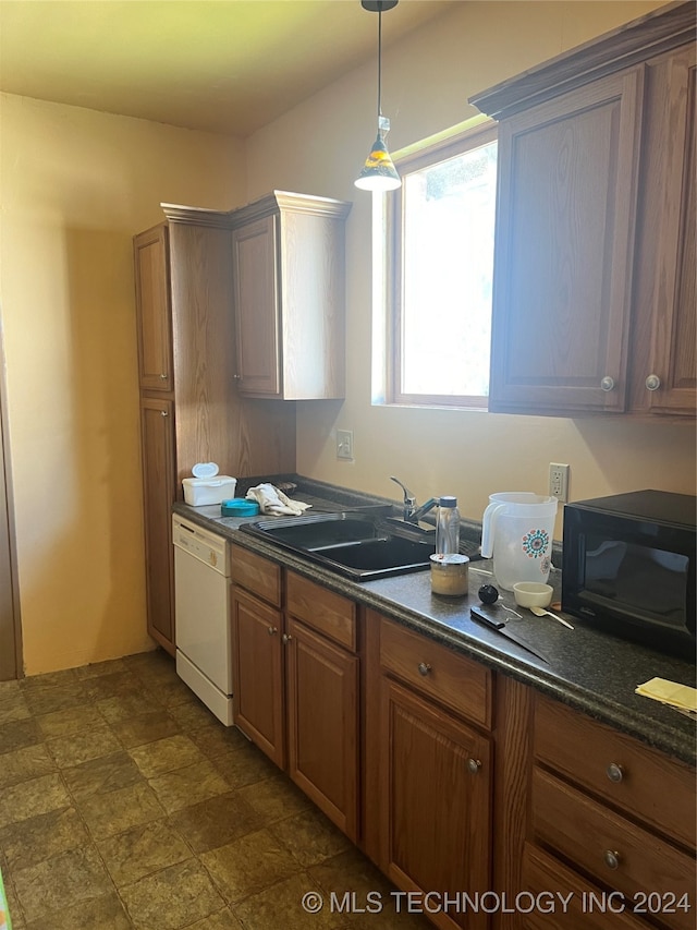 kitchen featuring decorative light fixtures, white dishwasher, dark tile patterned flooring, sink, and dark stone counters