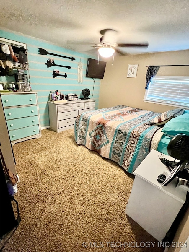 carpeted bedroom featuring ceiling fan and a textured ceiling