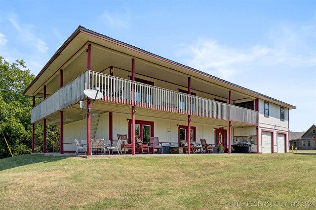 back of property with a balcony, a yard, and a garage