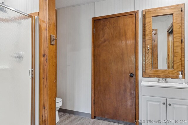 bathroom with vanity, toilet, hardwood / wood-style flooring, and a shower with shower door