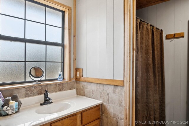 bathroom featuring a wealth of natural light, vanity, and tile walls