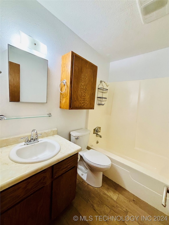 full bathroom with toilet, hardwood / wood-style floors, vanity, a textured ceiling, and bathtub / shower combination