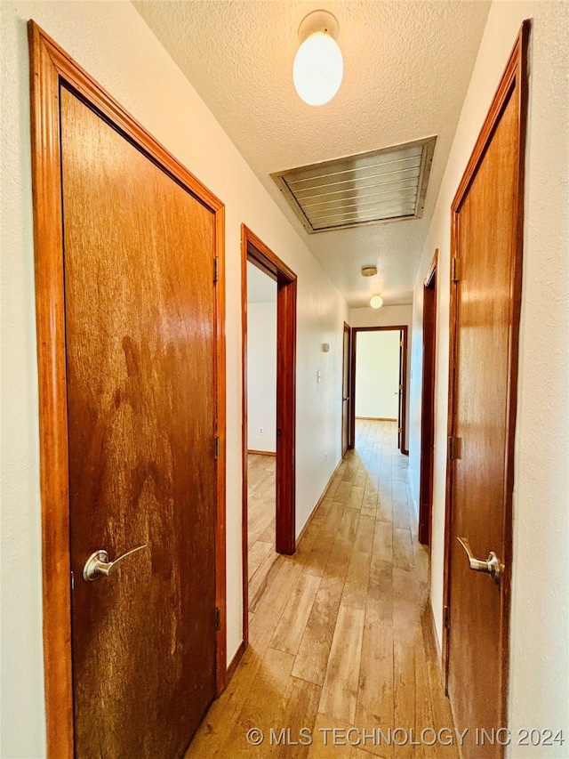 hallway featuring a textured ceiling and light wood-type flooring