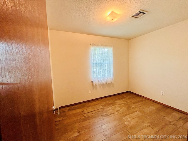 unfurnished room featuring wood-type flooring and a textured ceiling