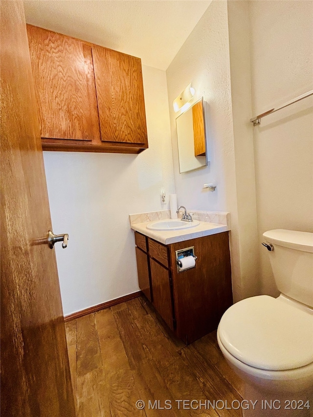 bathroom featuring toilet, hardwood / wood-style flooring, and vanity