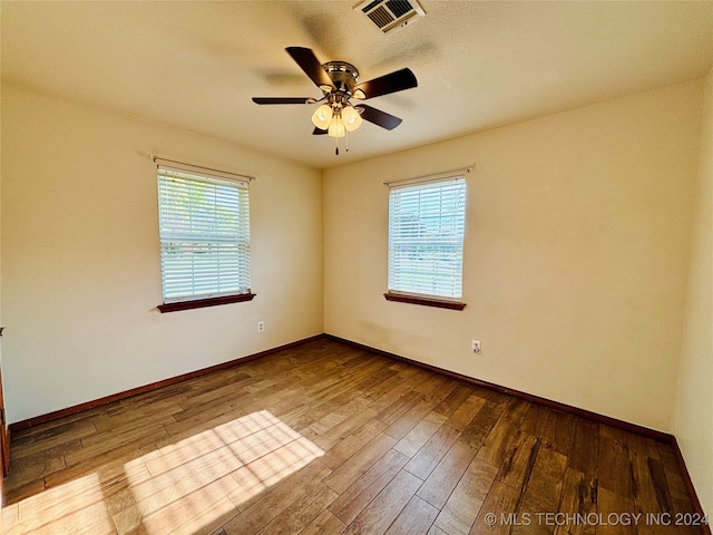 spare room featuring a wealth of natural light, ceiling fan, and hardwood / wood-style floors