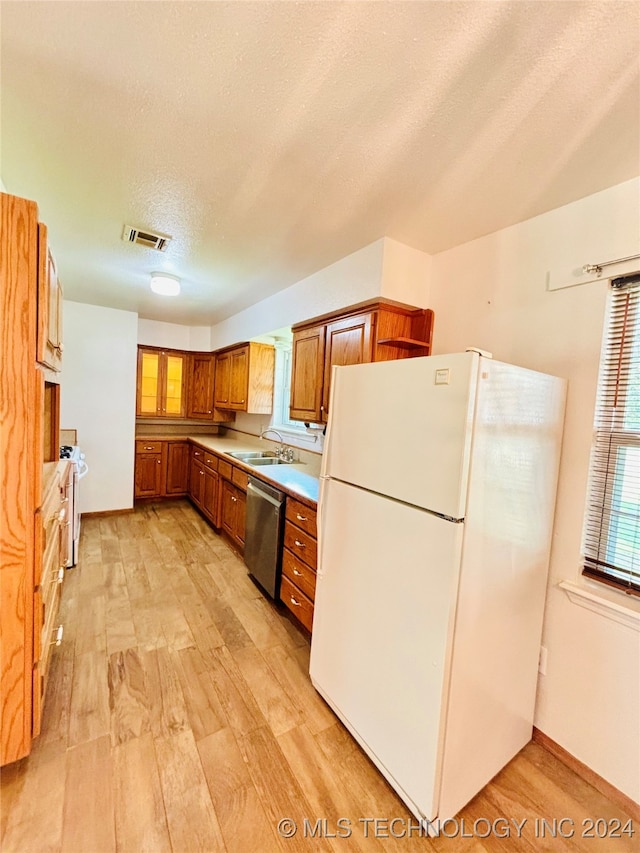 kitchen featuring a textured ceiling, light wood-type flooring, sink, and white appliances