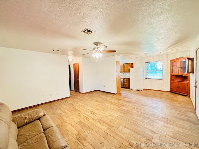 unfurnished living room featuring ceiling fan, light hardwood / wood-style floors, and a textured ceiling