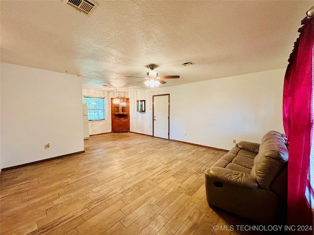 living room featuring a textured ceiling, ceiling fan, and light hardwood / wood-style floors