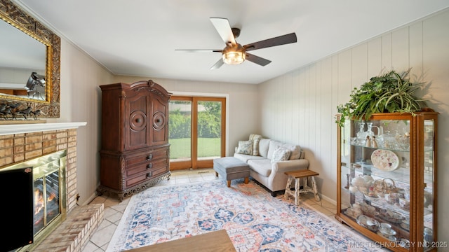 sitting room featuring ceiling fan, a fireplace, and light tile patterned floors