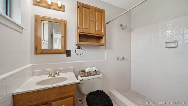 bathroom featuring tiled shower, vanity, toilet, and tile walls