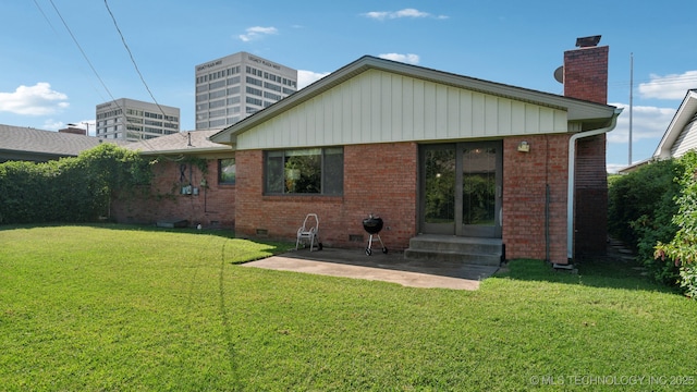 rear view of property featuring a lawn and a patio area