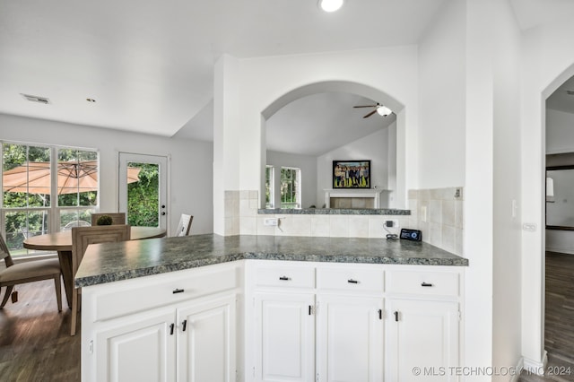 kitchen featuring white cabinetry, kitchen peninsula, backsplash, dark hardwood / wood-style flooring, and ceiling fan