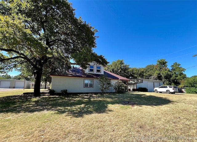 view of front facade featuring a front lawn, a garage, and an outbuilding