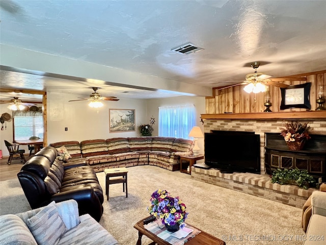 carpeted living room featuring a brick fireplace and ceiling fan