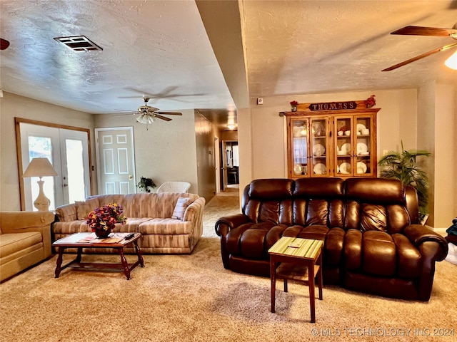 carpeted living room featuring a textured ceiling, ceiling fan, and french doors