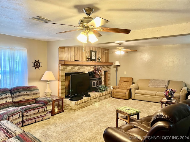 living room with a textured ceiling, a brick fireplace, ceiling fan, and carpet flooring