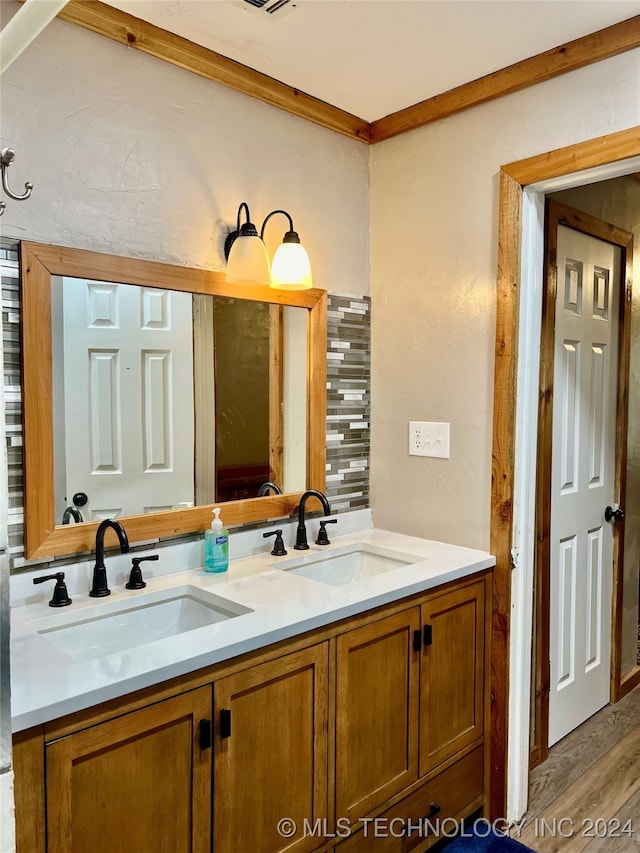 bathroom with wood-type flooring, ornamental molding, and vanity